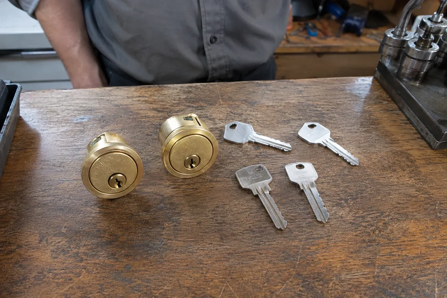 Two detached brass lock cylinders and four house keys on a wooden counter. — Lock Rekeying, Whitby